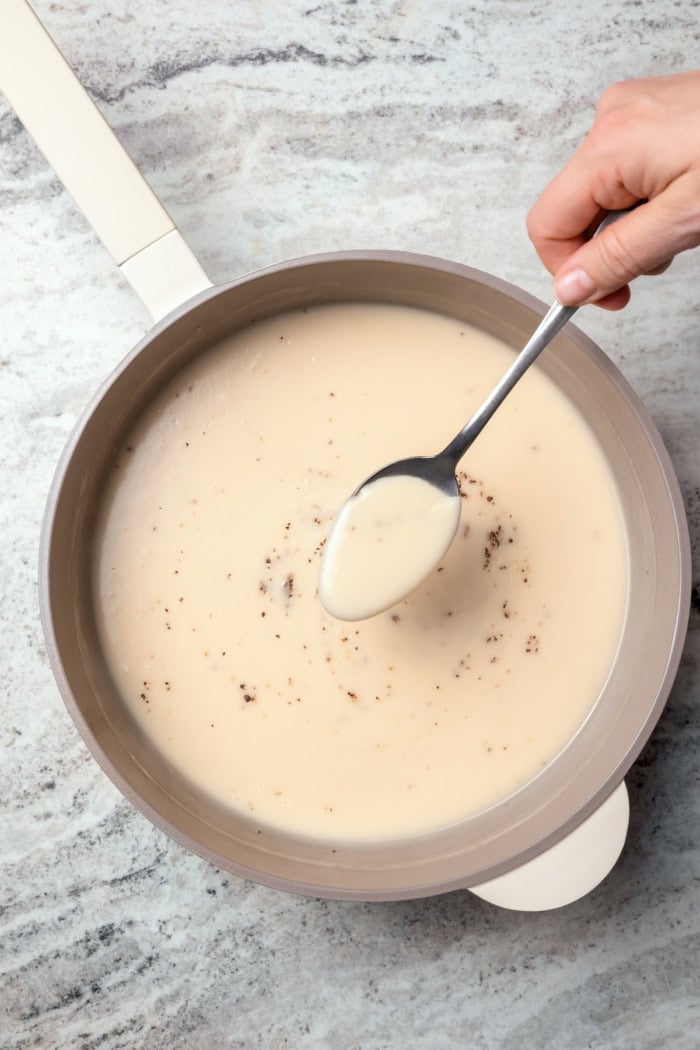 Spoonful of ham gravy held over pan.