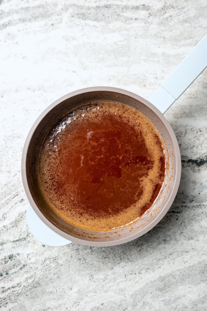 This Orange-Brown Sugar Ham Glaze is sweet and citrusy, but mustard, balsamic vinegar and warm spices add depth too. Easy and delicious! Saucepan with orange-brown sugar ham glaze.