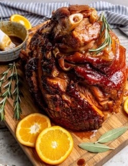 Ham on cutting board after being brushed with orange-brown sugar ham glaze.