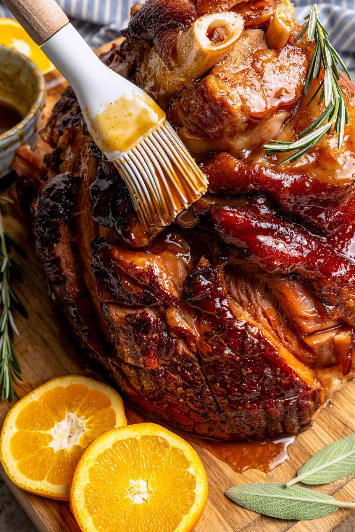 This Orange-Brown Sugar Ham Glaze is sweet and citrusy, but mustard, balsamic vinegar and warm spices add depth too. Easy and delicious! Brushing orange-brown sugar ham glaze onto ham.
