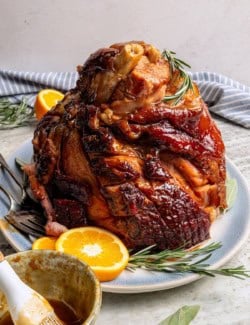 Platter with ham set next to bowl of orange-brown sugar ham glaze.