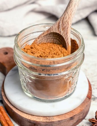 a small jar of Pumpkin Pie Spice, with a wooden spoon in the jar