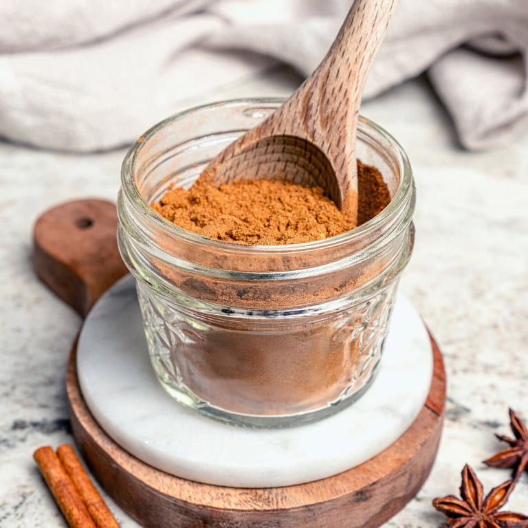 a small jar of Pumpkin Pie Spice, with a wooden spoon in the jar