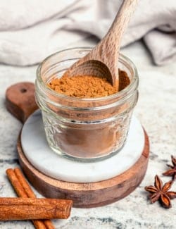a small jar of Pumpkin Pie Spice, with a wooden spoon in the jar