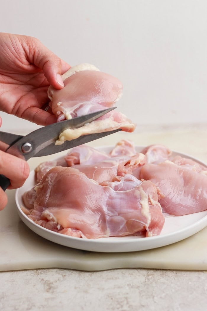 Trimming boneless skinless chicken thighs.