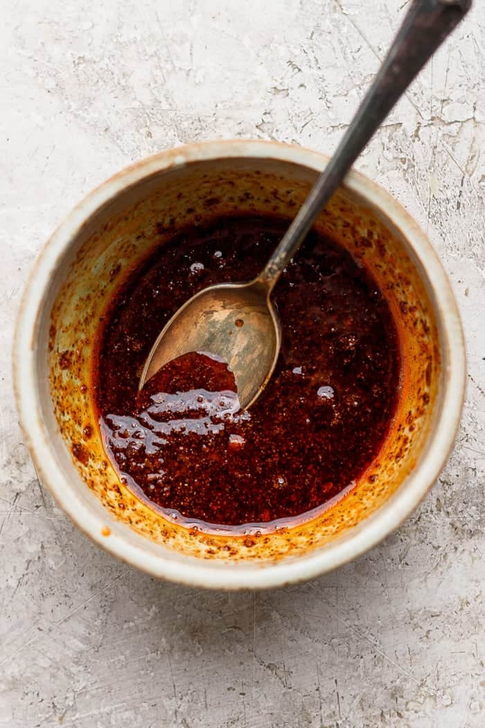 Oil, honey, and seasonings in bowl with spoon.