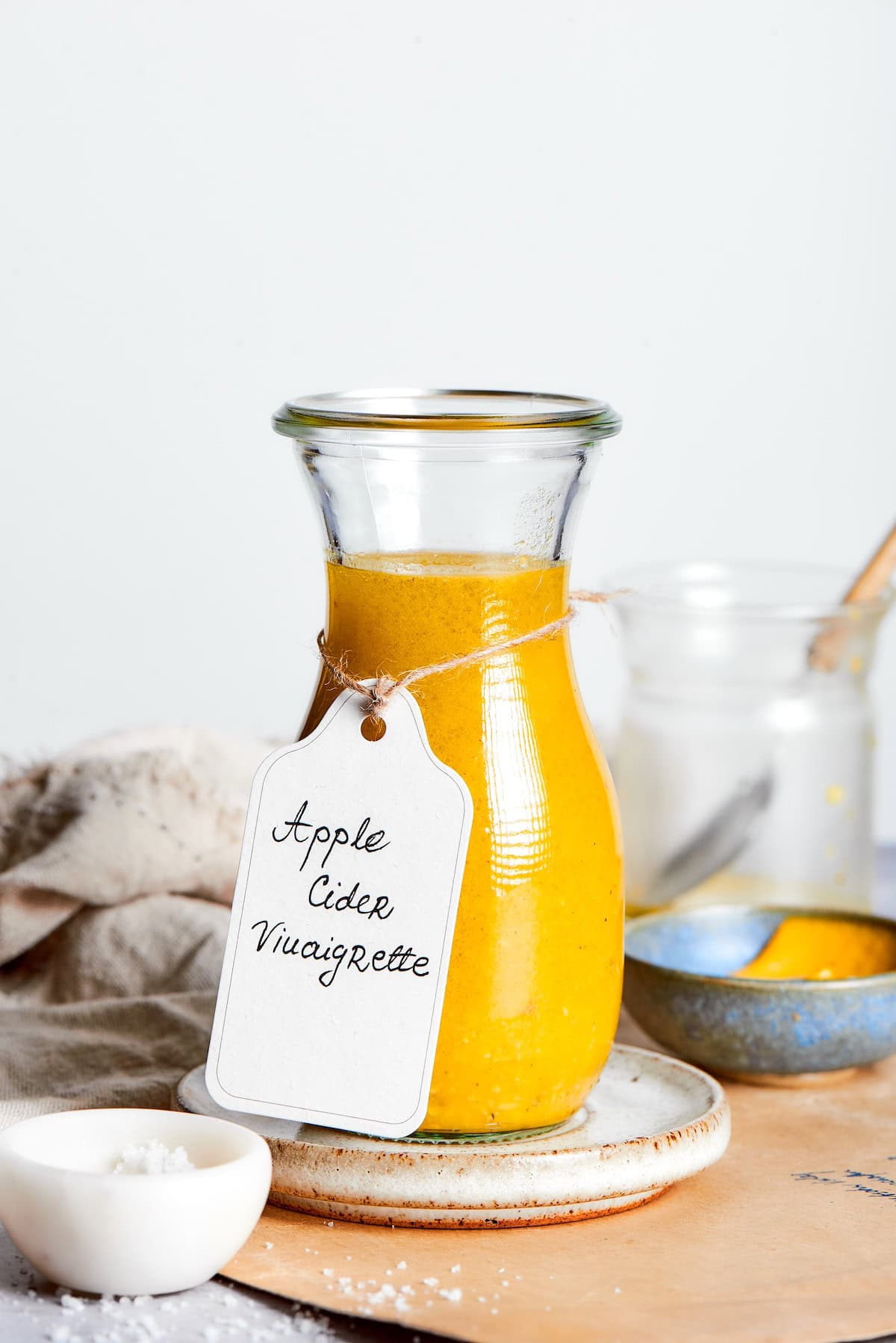 Homemade apple cider vinaigrette in glass bottle with tag tied around neck.
