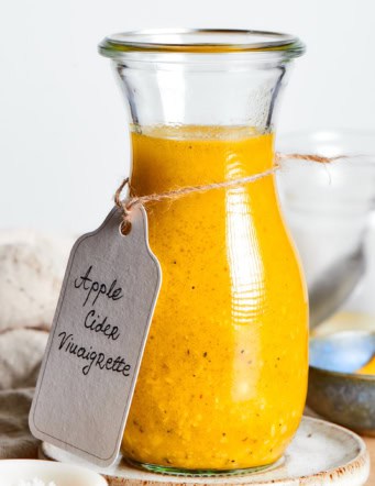 a jar of dressing with a handwritten label tied around it that says "Apple Cider Vinaigrette"