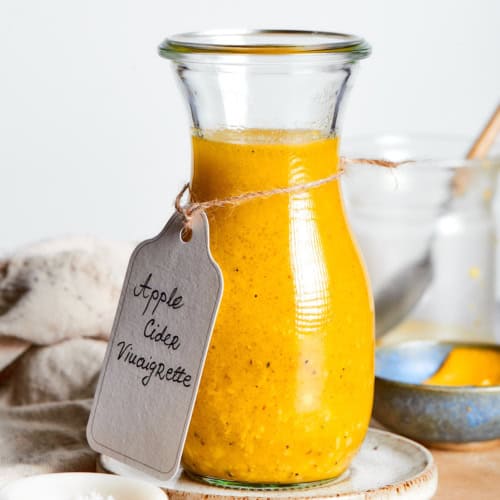 a jar of dressing with a handwritten label tied around it that says "Apple Cider Vinaigrette"
