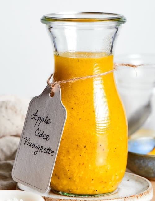 a jar of dressing with a handwritten label tied around it that says "Apple Cider Vinaigrette"