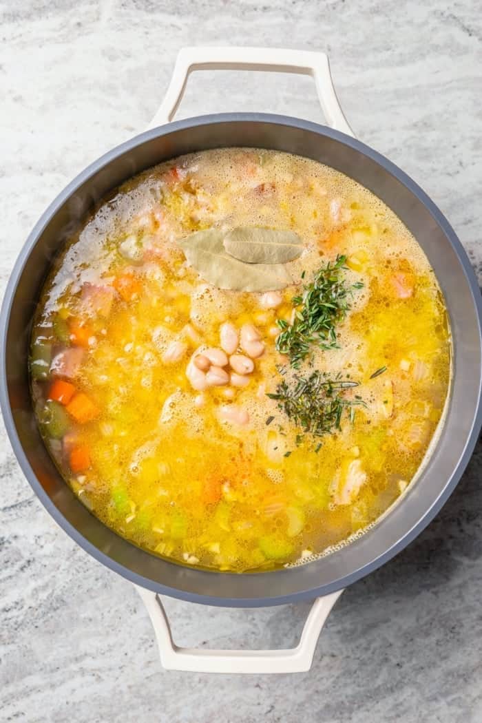 Fresh rosemary, thyme, and bay leaves added to pot of ham and bean soup.