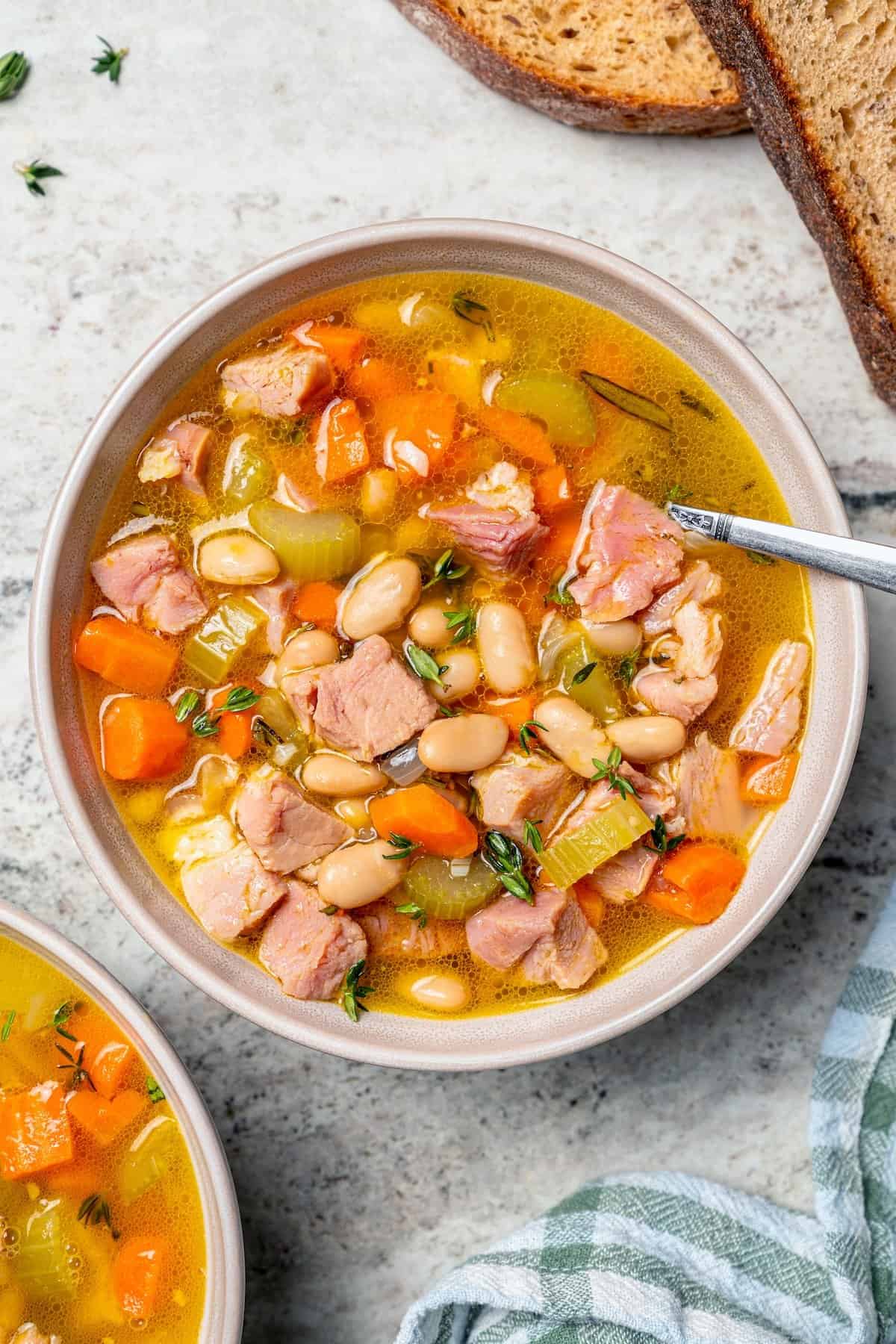Spoon in bowl of ham and bean soup.
