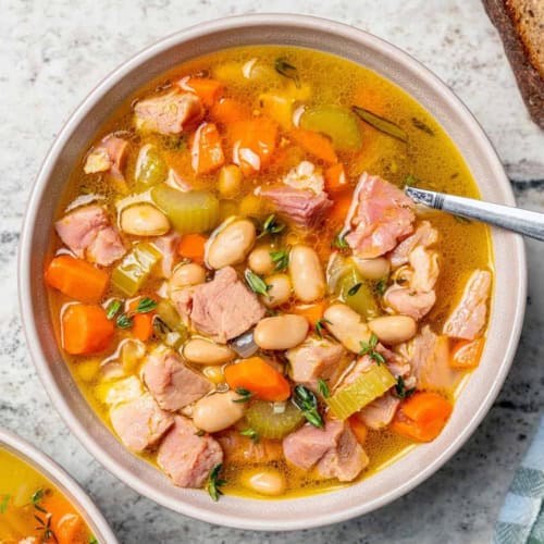 overhead photo of ham and bean soup in a white bowl