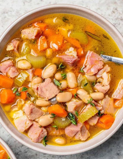 overhead photo of ham and bean soup in a white bowl