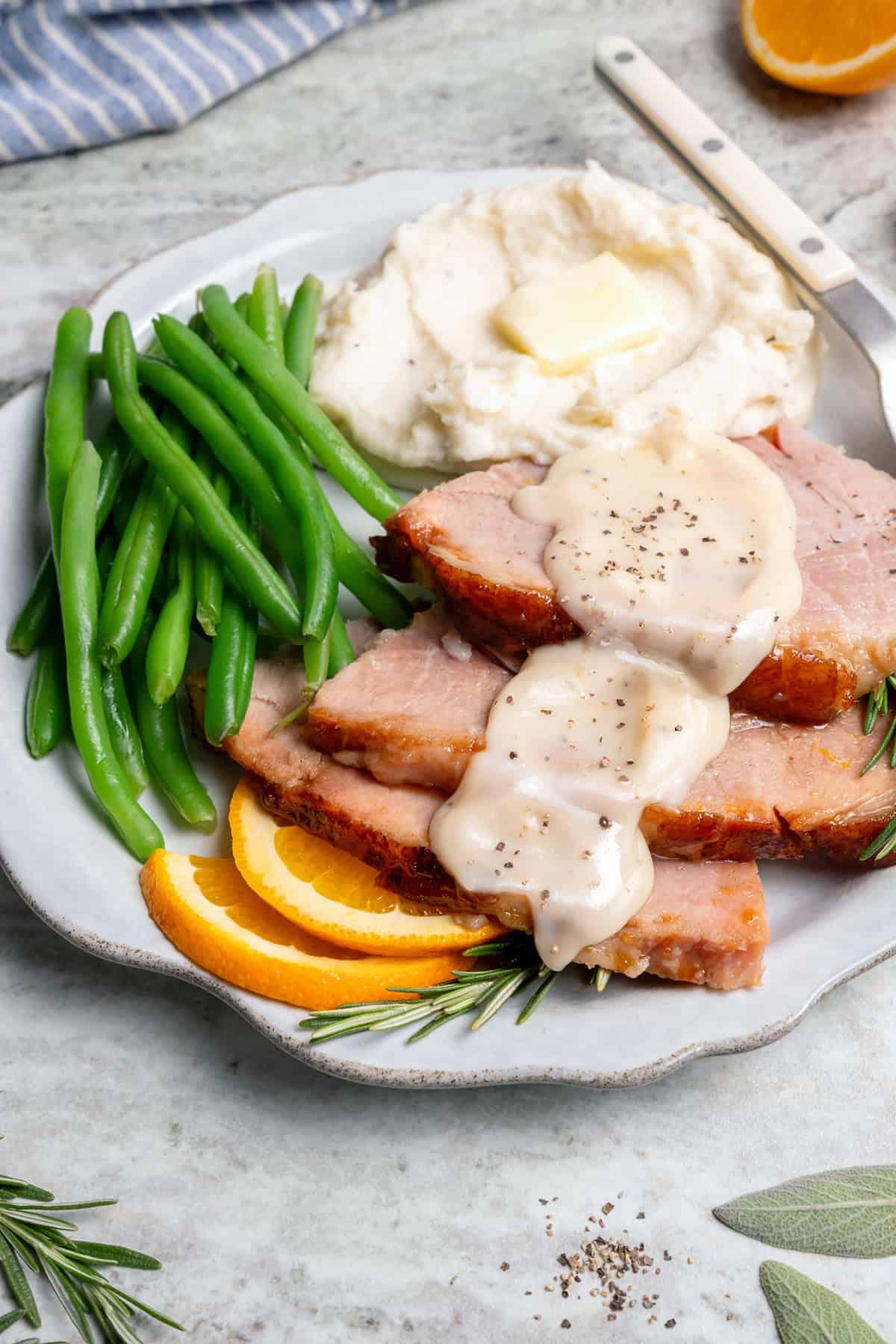 a plate of green beans, mashed potatoes, and sliced ham with ham gravy