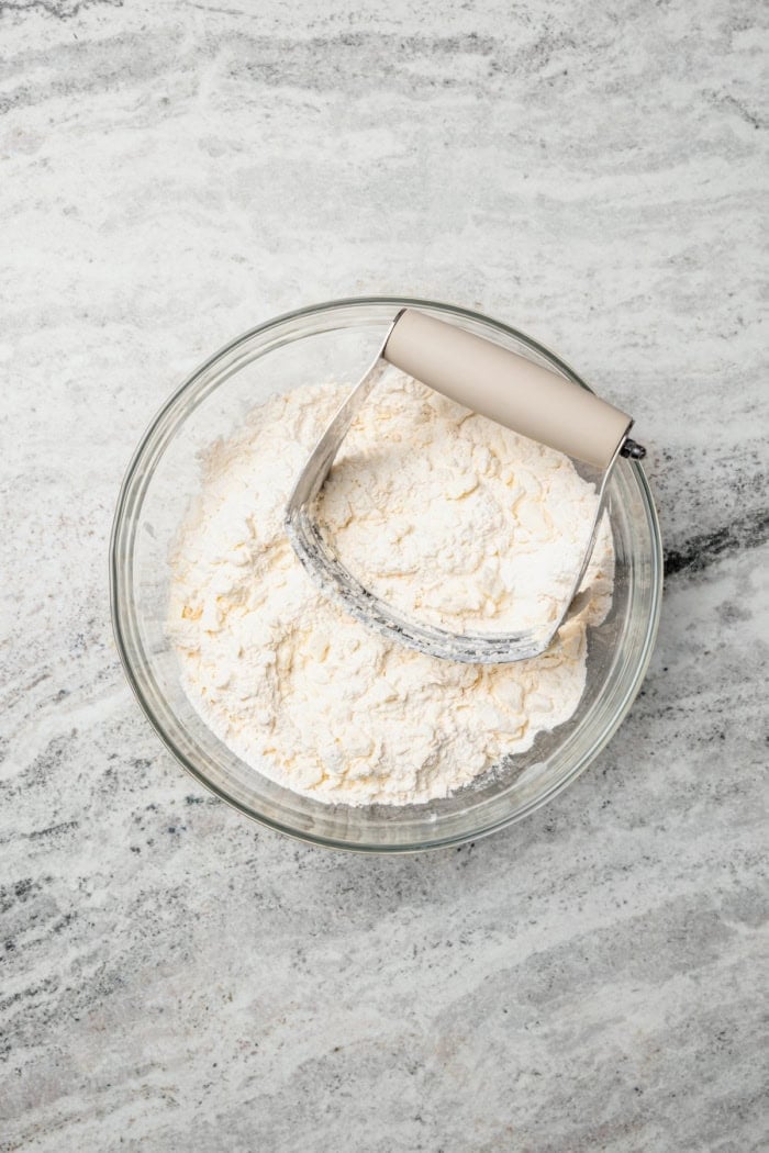 These Pecan Pie Bars have a caramel filling, buttery shortbread crust and NO corn syrup! Honey and brown sugar adds the perfect sweetness. Pastry blender in bowl with shortbread ingredients.