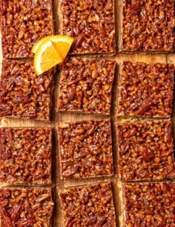 Overhead view of sliced pecan pie bars on cutting board.