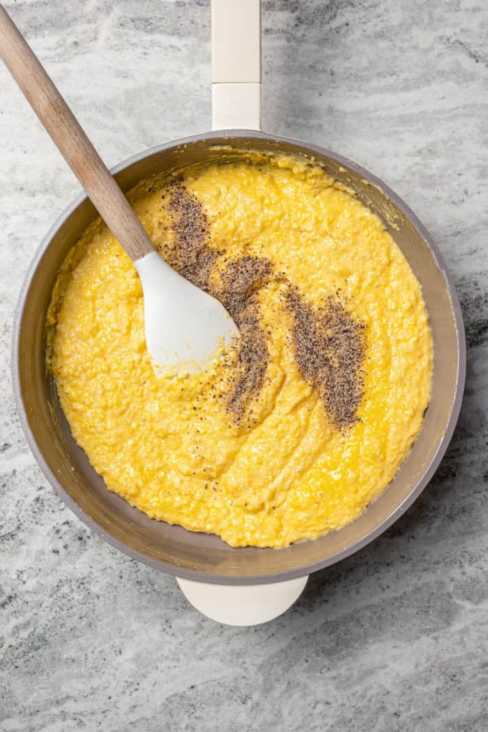 Stirring black pepper into cornmeal mixture in skillet.