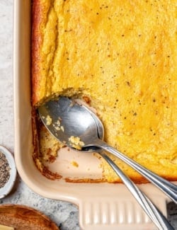 Spoon bread in casserole dish with two spoons.