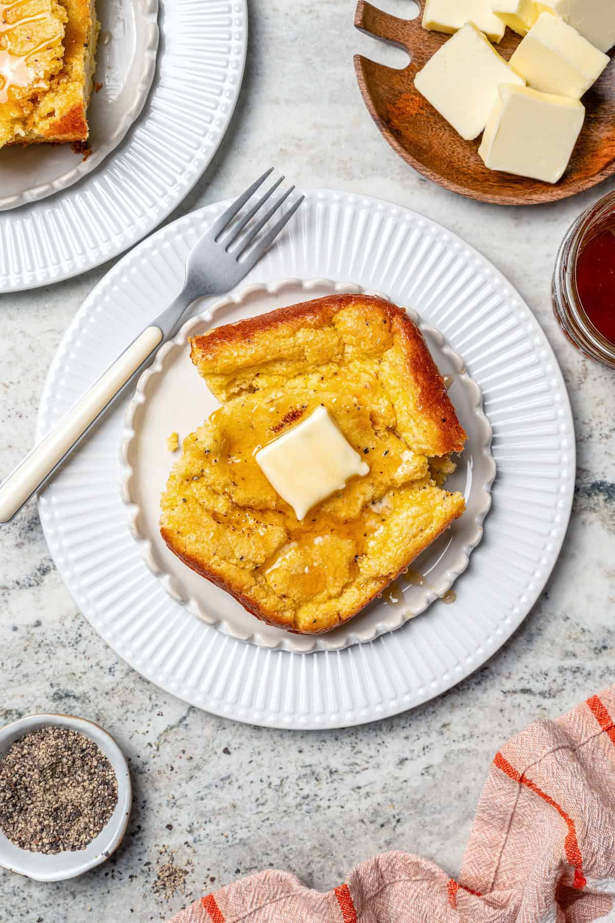 Spoon bread on plate with honey and butter.