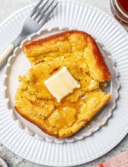 Plate with portion of spoon bread topped with honey and butter.