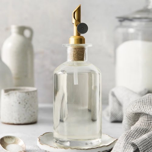 a clear bottle with a gold pour spout on top, full of simple syrup