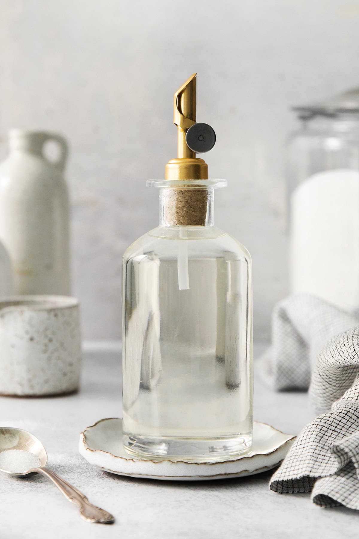 a clear bottle with a gold pour spout that has simple syrup in it