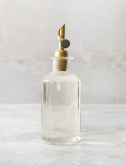 a clear bottle with a gold pour spout, full of simple syrup