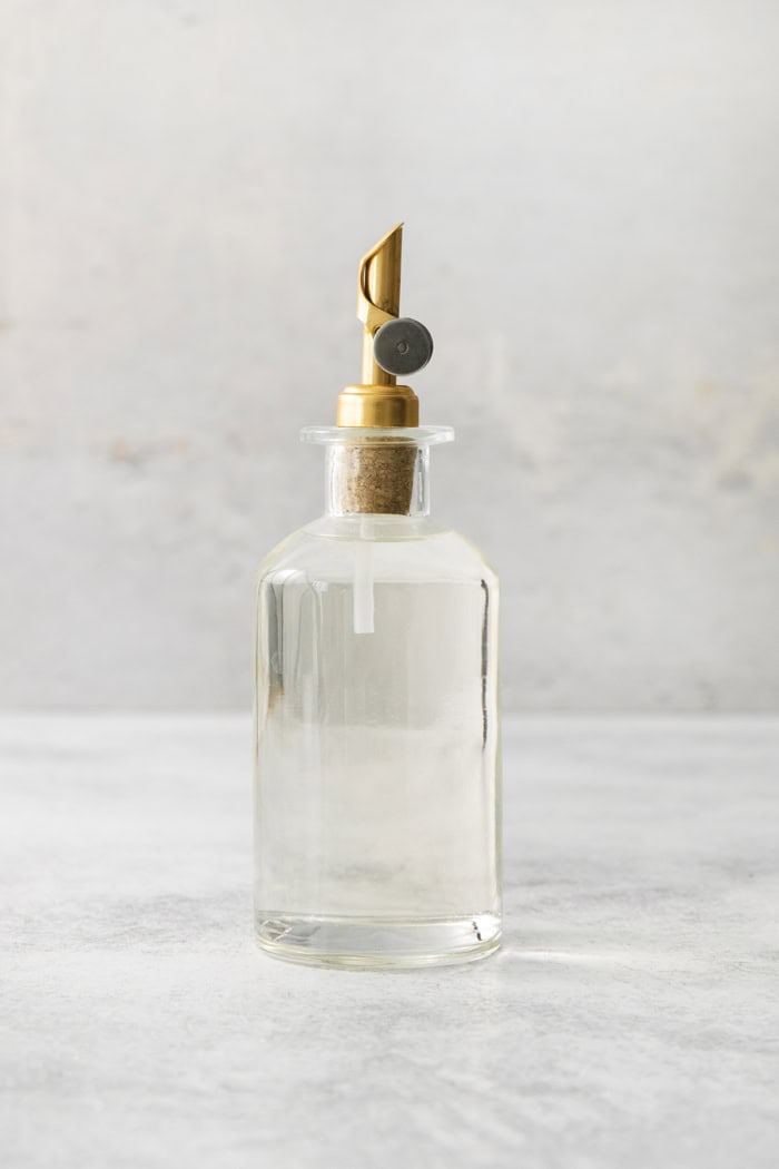 a clear bottle with a gold pour spout, full of simple syrup