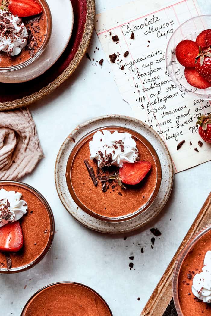 overhead photo of chilled chocolate mousse cups garnished with whipped cream and strawberries