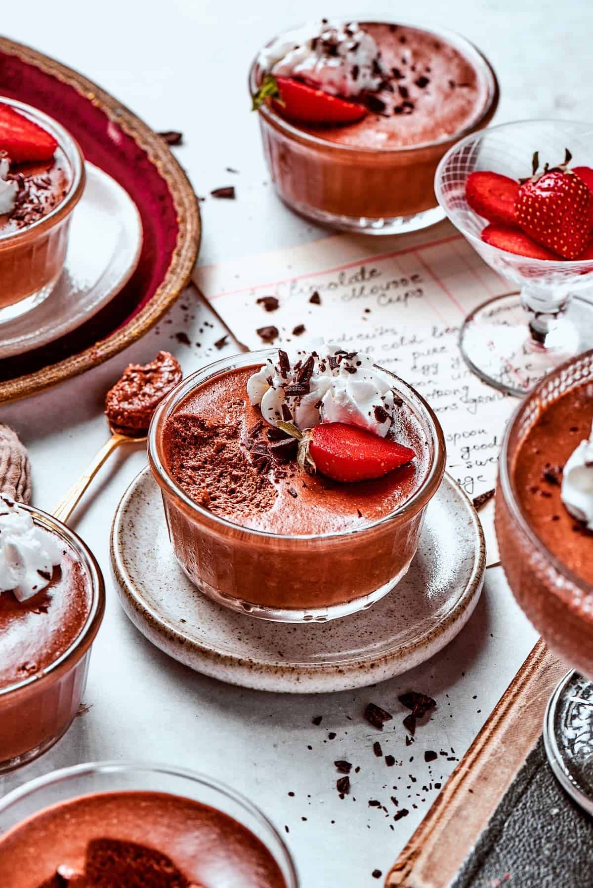 several cups of chocolate mousse with whipped cream and strawberries