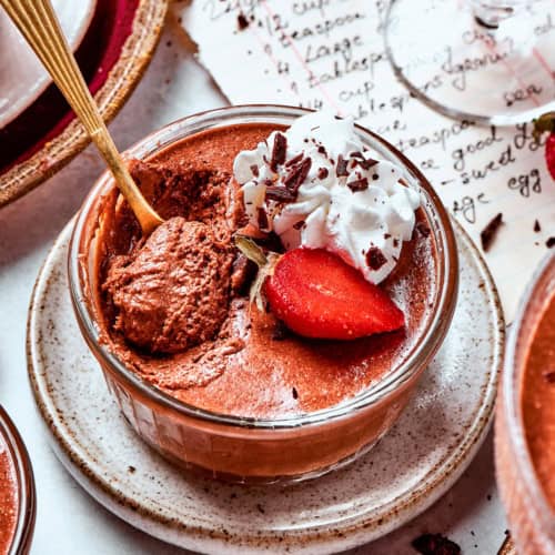 a cup of chocolate mousse with whipped cream and strawberries
