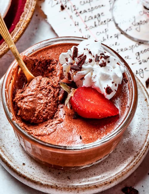 a cup of chocolate mousse with whipped cream and strawberries