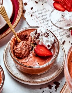 a cup of chocolate mousse with whipped cream and strawberries