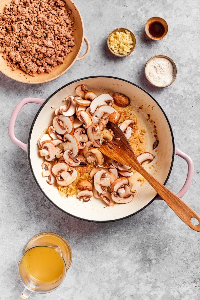 Sliced cremini mushrooms added to skillet.