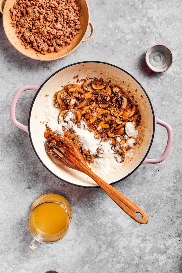 Flour added to pan of sauteed mushrooms.