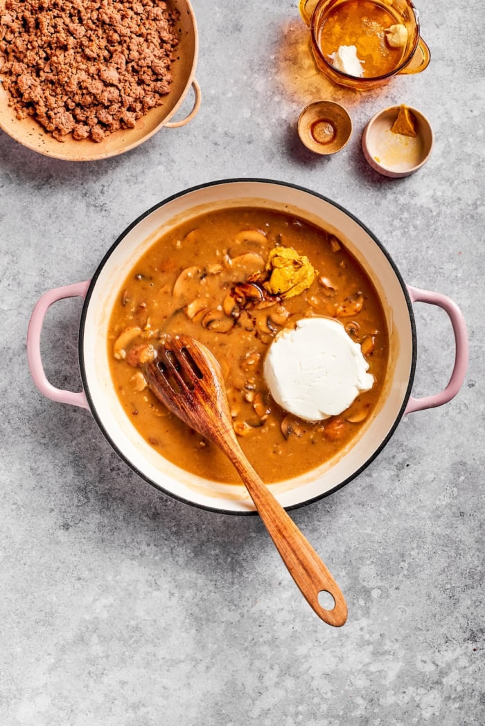 Sour cream and mustard added to pan of ground beef stroganoff sauce.