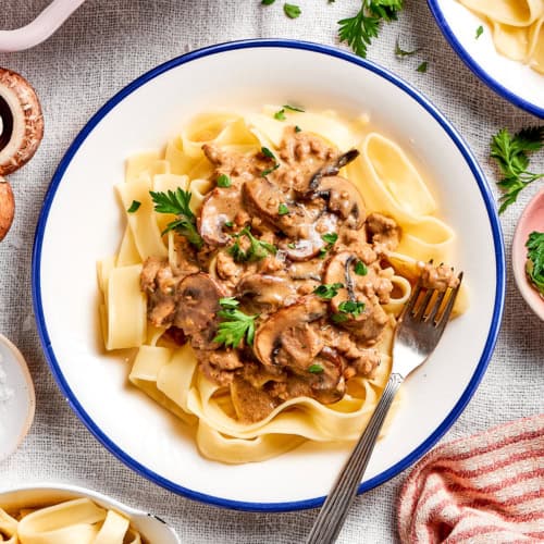 ground beef stroganoff on a white plate with a blue rim
