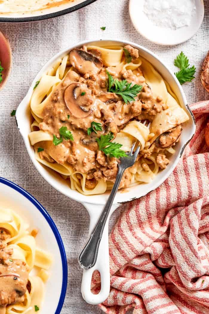 Noodle twirled around fork in skillet of ground beef stroganoff.