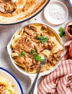a small white skillet of ground beef stroganoff over egg noodles