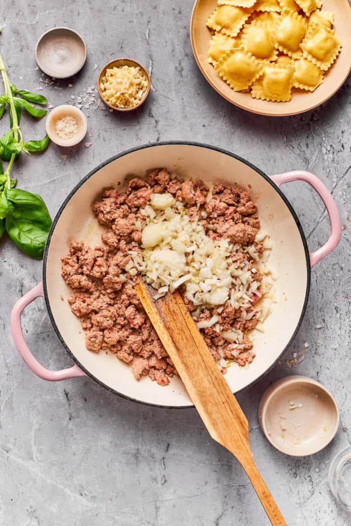 Onion added to ground beef in pan.