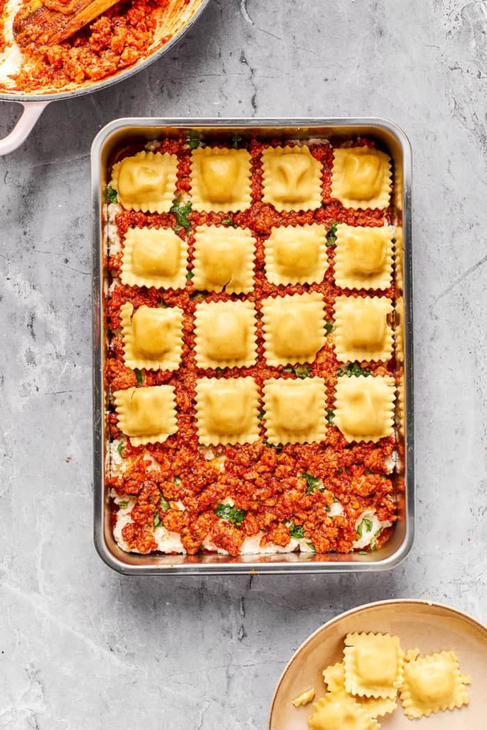 Layer of ravioli being added to lasagna pan.
