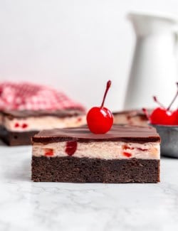 side view of a cherry chocolate brownie with a maraschino cherry on top