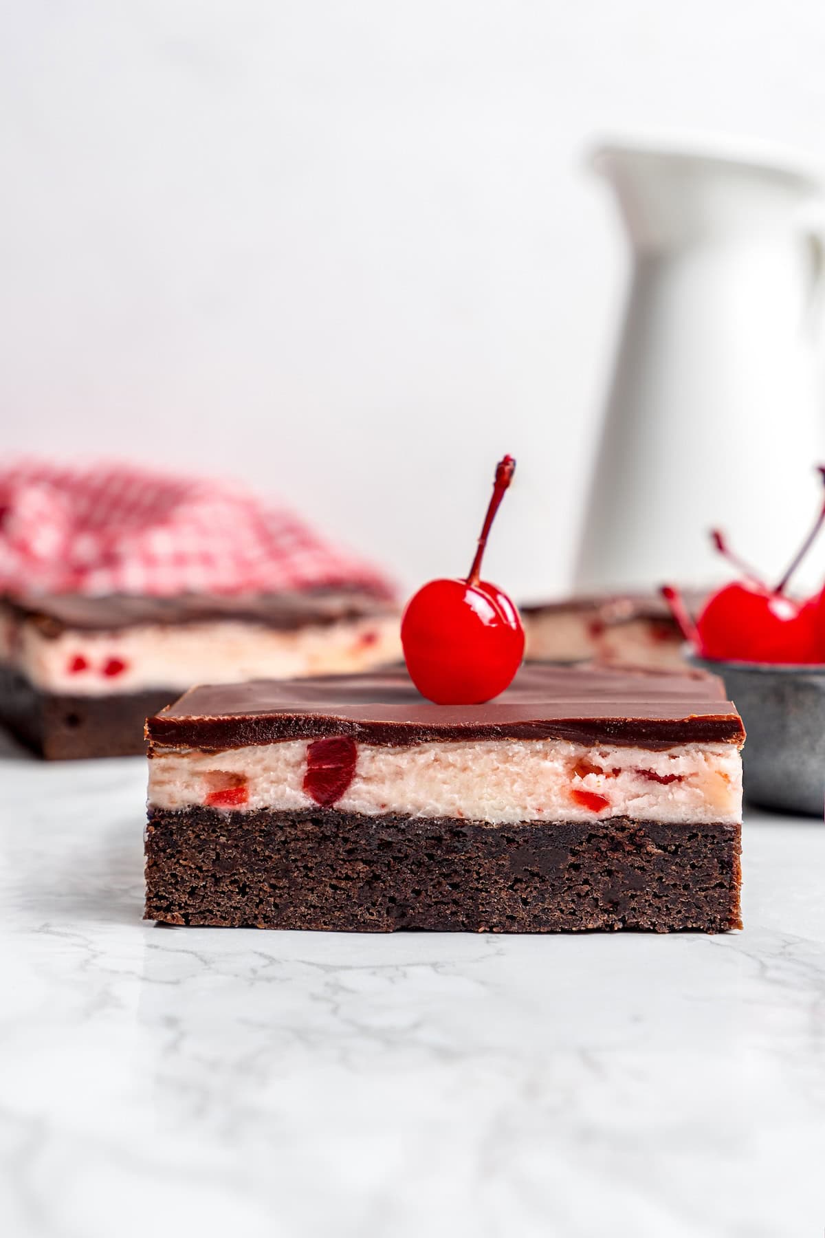 side view of a cherry chocolate brownie with a maraschino cherry on top