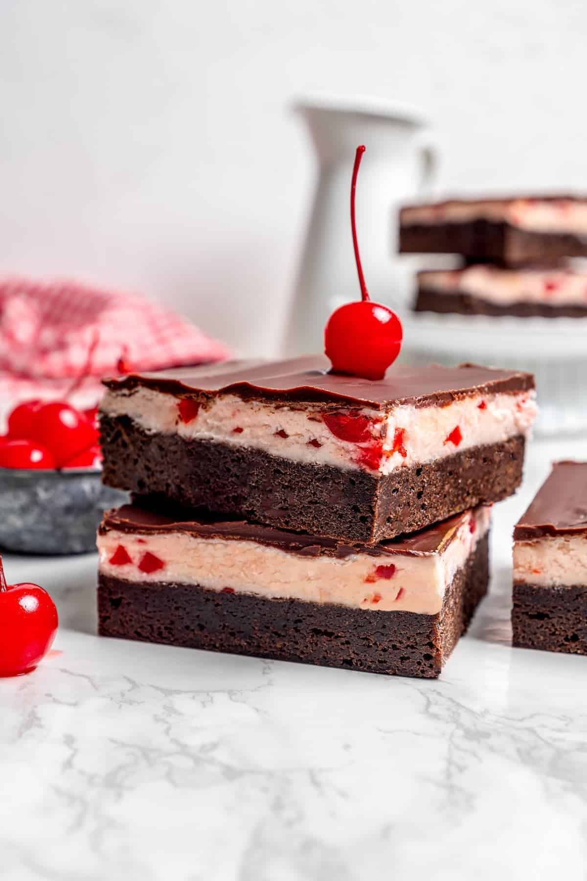 side view of a stack of cherry chocolate brownies with a maraschino cherry on top