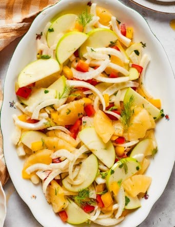 overhead photo of a white platter with fennel, apple, and pineapple salad