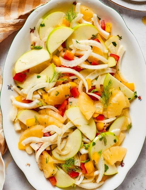 overhead photo of a white platter with fennel, apple, and pineapple salad