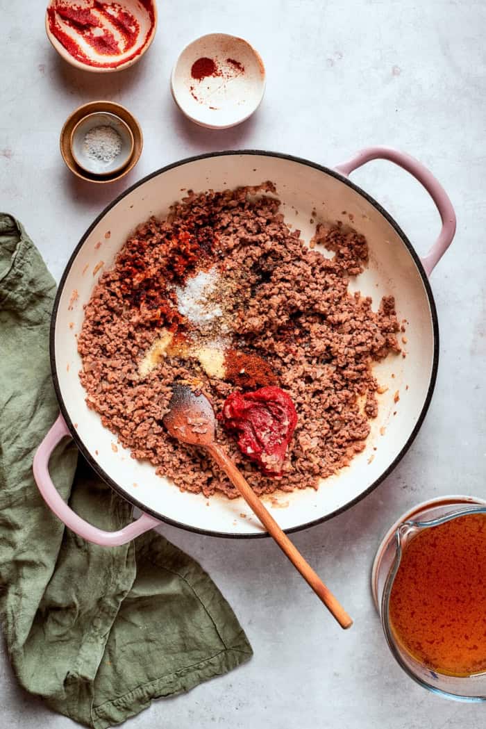 Tomato paste and spices added to skillet of browned ground beef.