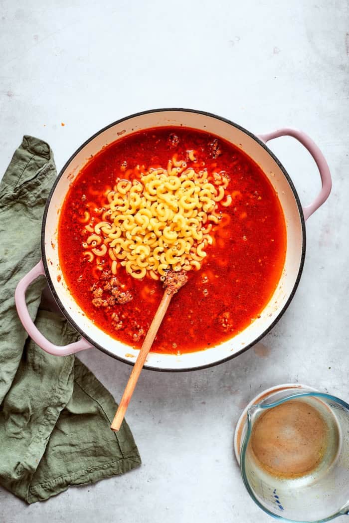 Elbow macaroni added to skillet of ground beef and broth.