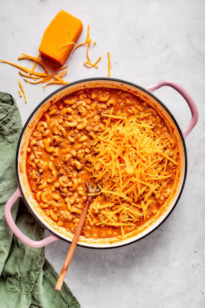 Shredded cheddar added to pan of hamburger helper.